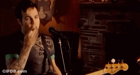 Man Playing Guitar And Singing Into Microphone While Smoking GIF