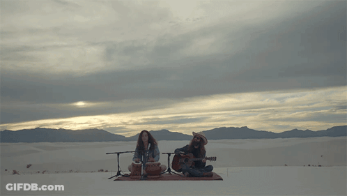 Man Playing Guitar And Woman Playing Drum In Desert GIF