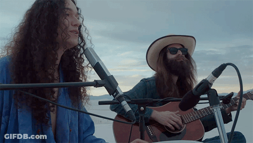 Man Playing Guitar And Woman Playing Drum In Desert GIF