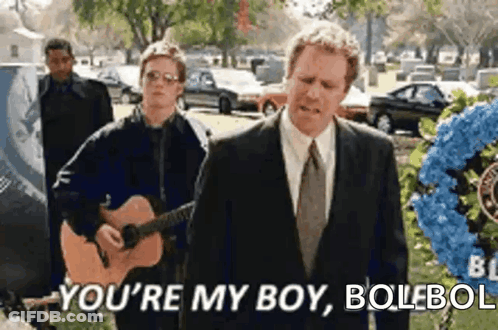 Man Playing Guitar At Funeral With Man Behind GIF