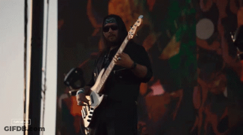 Man Playing Guitar In Front Of Cacahua Screen GIF