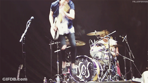 Man Playing Guitar In Front Of Drum Set Saying SOS GIF
