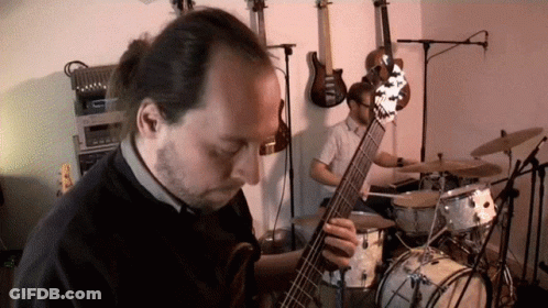 Man Playing Guitar In Front Of Drums GIF