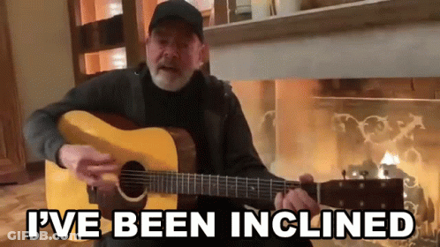Man Playing Guitar In Front Of Fireplace Saying I've Been Inclined GIF