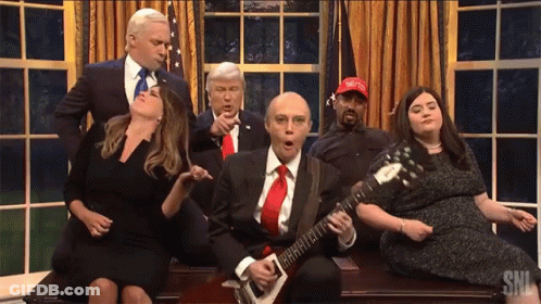 Man Playing Guitar In Front Of Group With MAGA Hat GIF