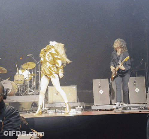 Man Playing Guitar Next To Woman On Stage GIF