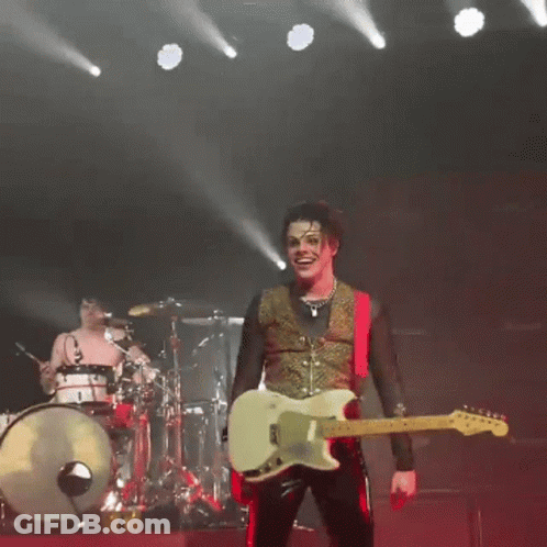 Man Playing Guitar On Stage In Front Of Drum Set GIF