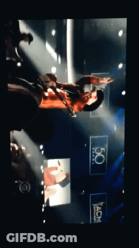 Man Playing Guitar On Stage With 50 Years ACM Sign GIF
