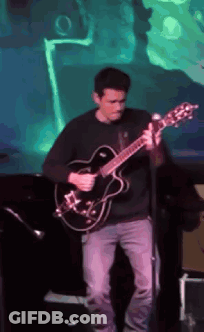 Man Playing Guitar On Stage With Green Background GIF
