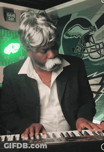 Man Playing Piano In Front Of Game Day Sign GIF
