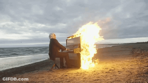 Man Playing Piano With Flames On Beach GIF