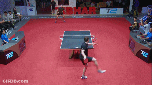Man Playing Ping Pong In Front Of T2 Sign GIF