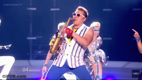 Man Playing Saxophone In Front Of Eurovision TV Screen GIF