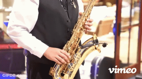 Man Playing Saxophone In Front Of Vimeo Sign GIF