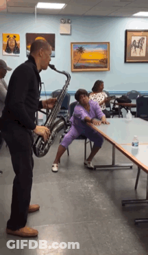 Man Playing Saxophone While Woman Sits On Table GIF