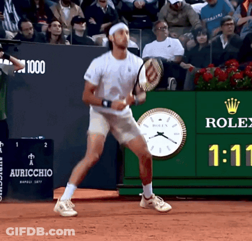 Man Playing Tennis In Front Of Rolex Clock GIF