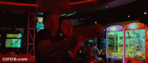 Man Playing Video Game In Arcade With Claw Machine GIF