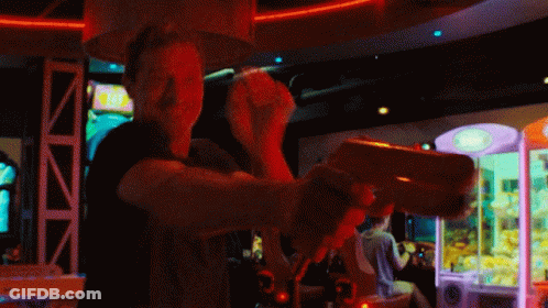 Man Playing Video Game In Dark Room With Claw Machine GIF