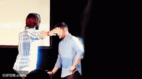Man Pointing At Another Man's Head In Front Of Screen GIF