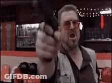 Man Pointing Gun At Camera In Bowling Alley GIF