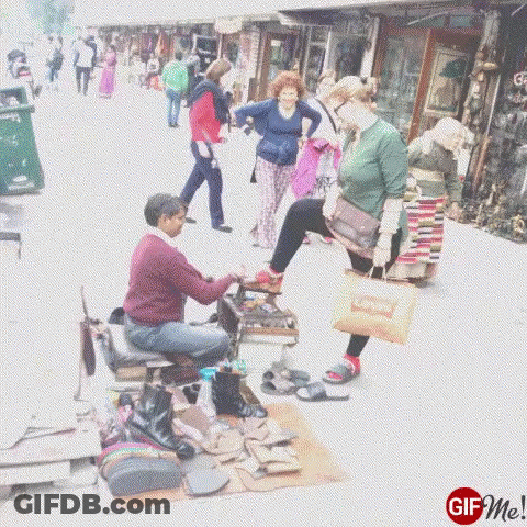Man Polishing Woman's Shoe On Sidewalk GIF