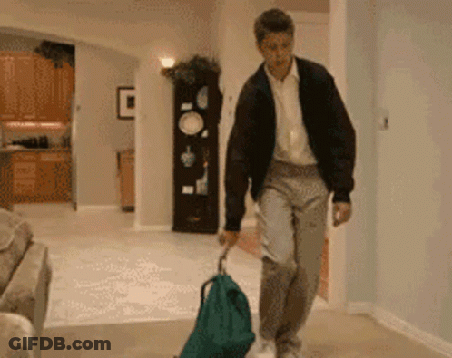 Man Pulling Green Bag On Trolley GIF