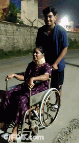 Man Pushes Woman In Wheelchair Down Street GIF