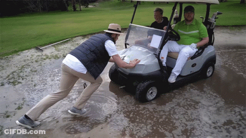 Man Pushing Golf Cart Through Muddy Field GIF