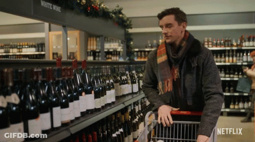 Man Pushing Shopping Cart Past White Wine Shelf GIF
