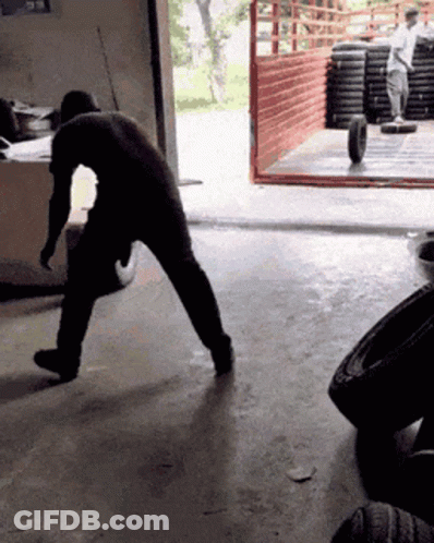 Man Pushing Tire In Garage GIF