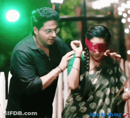 Man Putting Red Blindfold On Woman With Sparks Flying GIF