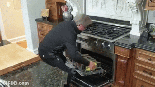 Man Putting Something In Oven In Kitchen GIF