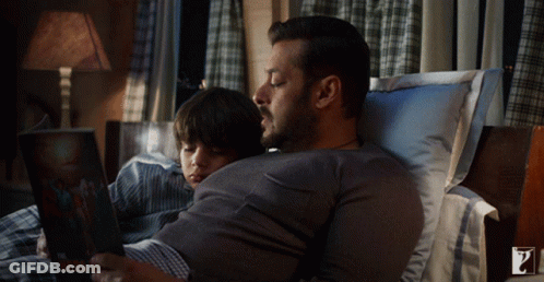 Man Reading Book To Boy Lying On Stomach GIF