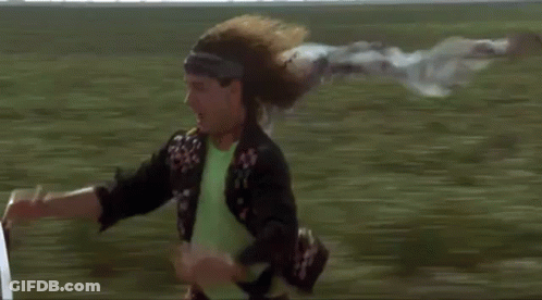 Man Riding Bicycle With Flying Scarf In Field GIF