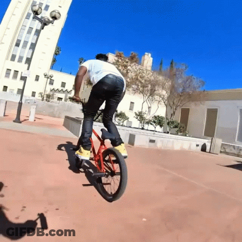 Man Riding Bike In Front Of Building GIF