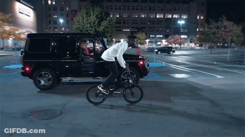 Man Riding Bike Next To Black SUV GIF