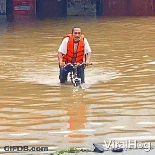 Man Riding Bike Through Flooded Street GIF