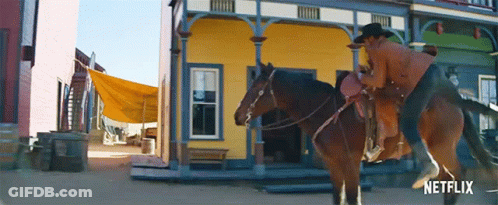 Man Riding Horse In Front Of Yellow Netflix Building GIF