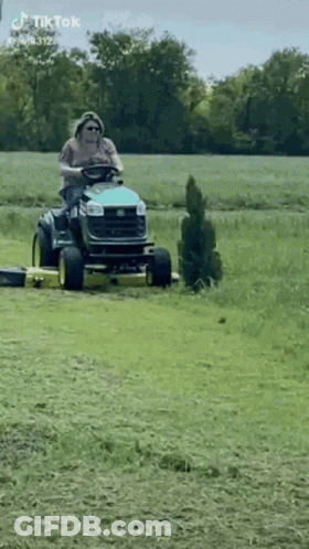 Man Riding Lawn Mower Through Field GIF
