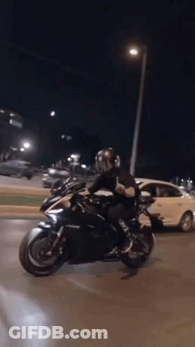Man Riding Motorcycle Down Street At Night GIF