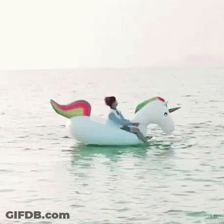 Man Riding Unicorn Float In Ocean GIF