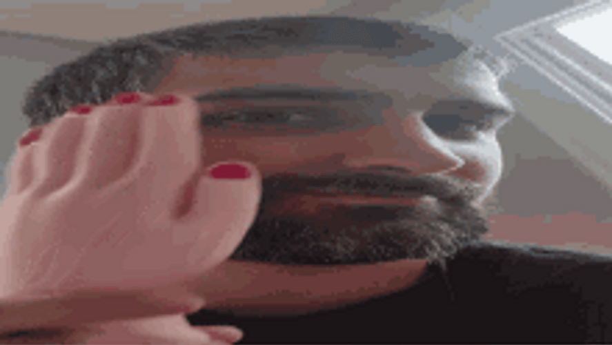 Man Rubbing Face Using Rubber Hand Toy GIF
