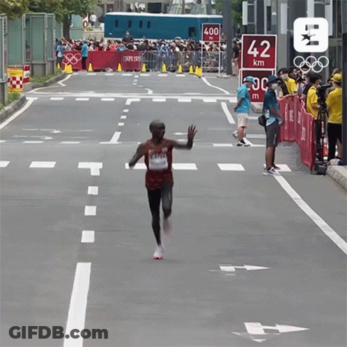 Man Running Down Street With 42 Km Sign GIF