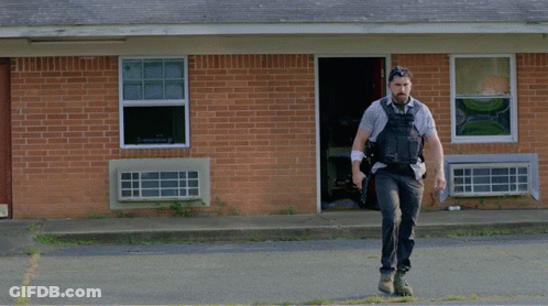 Man Running In Front Of Brick Building With Explosion GIF