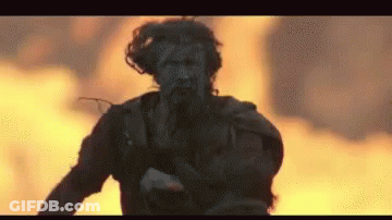 Man Running In Front Of Fire With Gun GIF