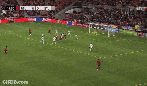 Man Running On Soccer Field In Front Of Nacho Nacho Sign GIF