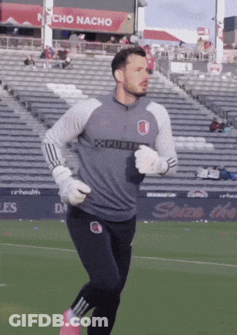 Man Running On Soccer Field In Front Of Nacho Nacho Sign GIF