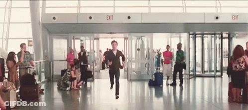 Man Running Through Airport With Exit Sign GIF