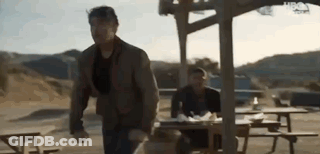 Man Running Towards Picnic Table While Another Man Sits GIF