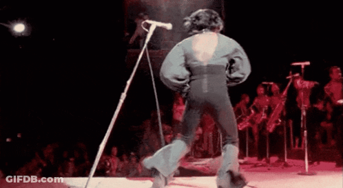 Man Singing Into Microphone And Dancing On Stage GIF